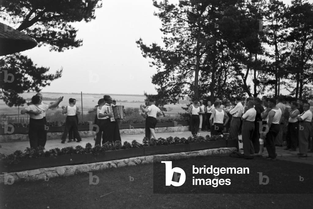 People singing and dancing in front of forest huts at the sports club at Belzig in Brandenburg, Germany 1930s (b/w photo)