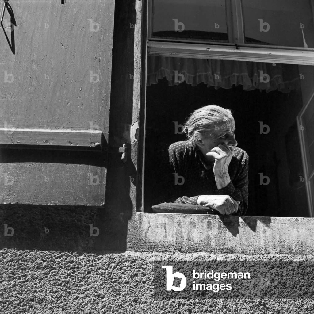 An old woman watching out of her window at Regensburg, Germany 1930s (b/w photo)