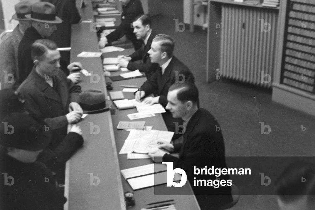 Travellers and staff members at a huge office of a travel agency in Berlin, Germany 1930s (b/w photo)