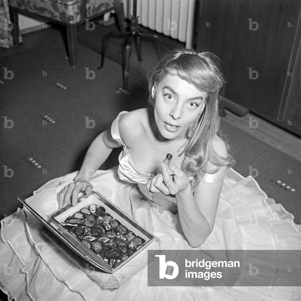 French singer Daniele Dupre eatimng pralines at a photo shoot in her hotel room at Hamburg, Germany 1950s
