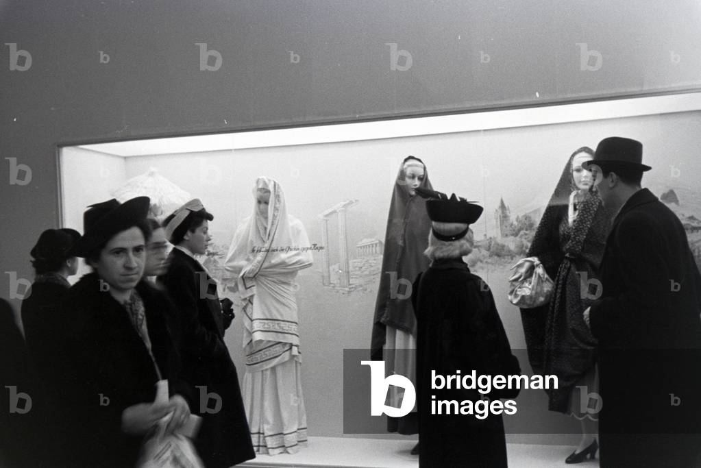 Visitors to a fair in front of a display case with traditional costumes, on the occasion of the Wiener Modewoche in the house of fashion 