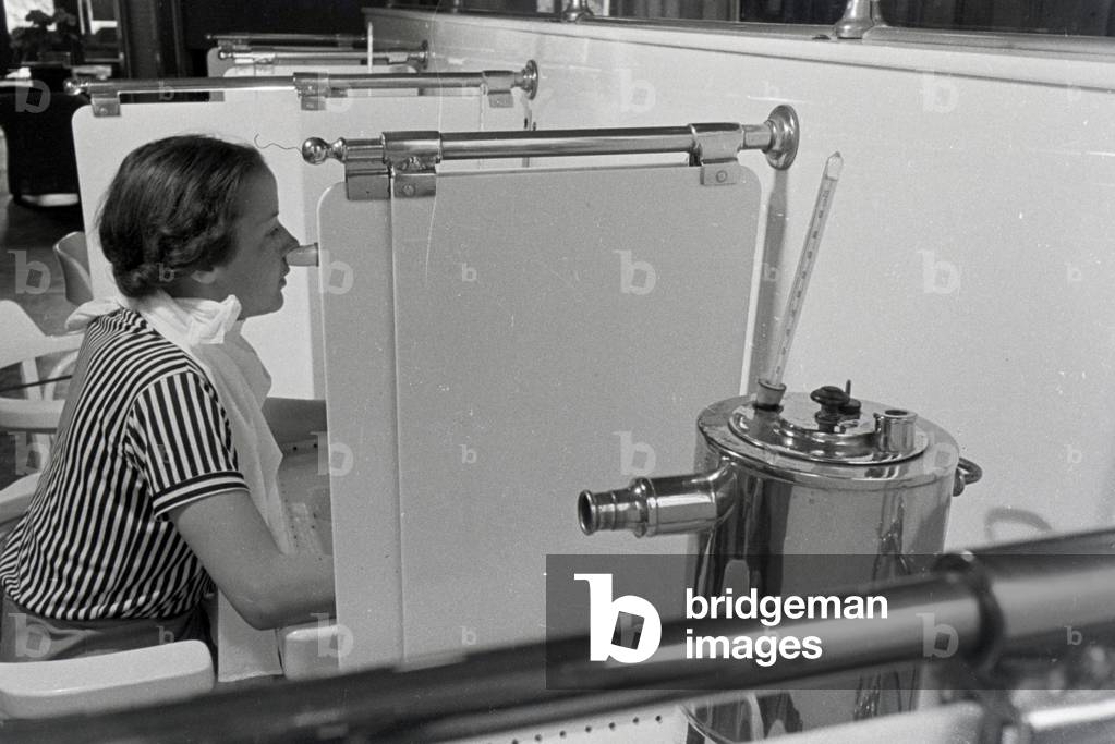 A young woman in the brine inhalation room during her visit of the Caracalla Therme in Baden-Baden, Germany 1930s (b/w photo)