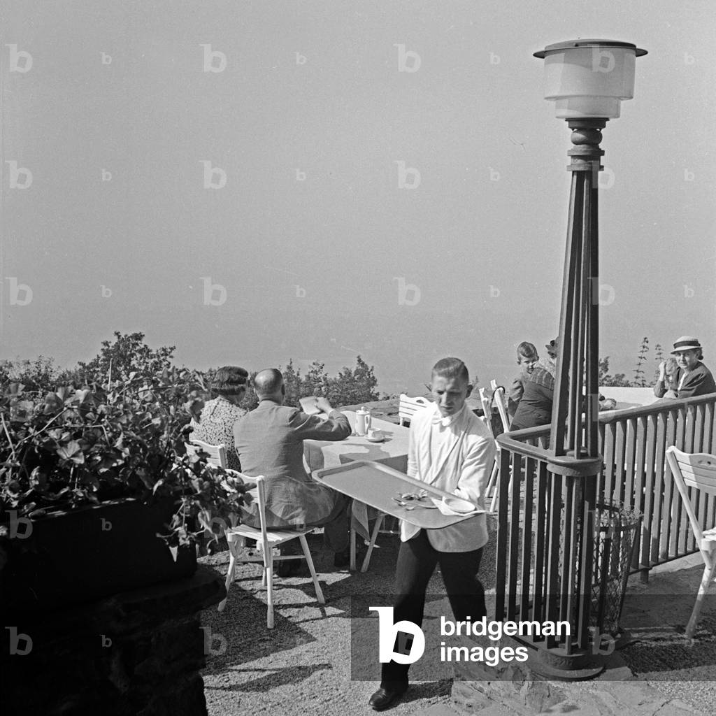 A waiter doing his daily business at the terrace of a restaurant, Germany 1930s (b/w photo)