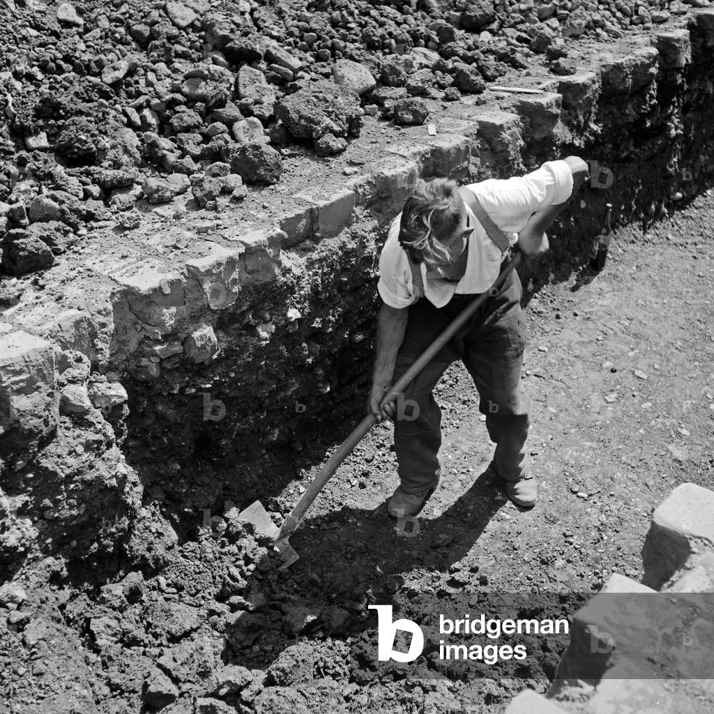 Construction worker digging at a construction area in Wuppertal, 1930s (b/w photo)