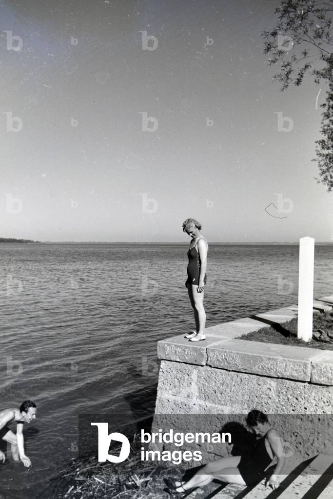 Two young women and a young man sunbathing and swimming in the Chiemsee, Dermany 1930s (b/w photo)