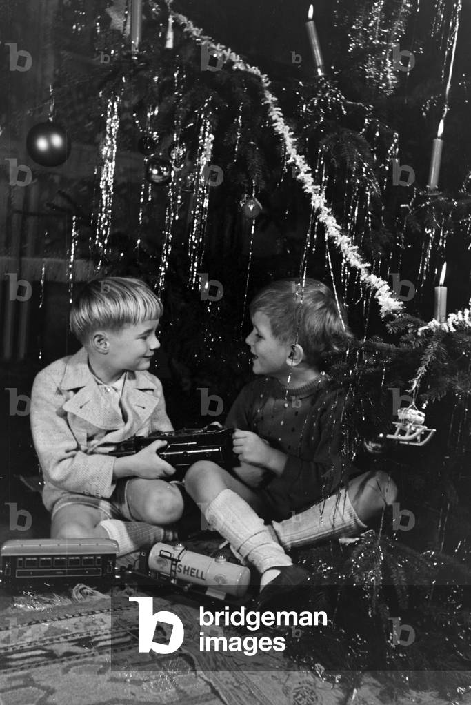 Two boys quarrelling about the new model train under the christmas tree, Germany 1930s (b/w photo)