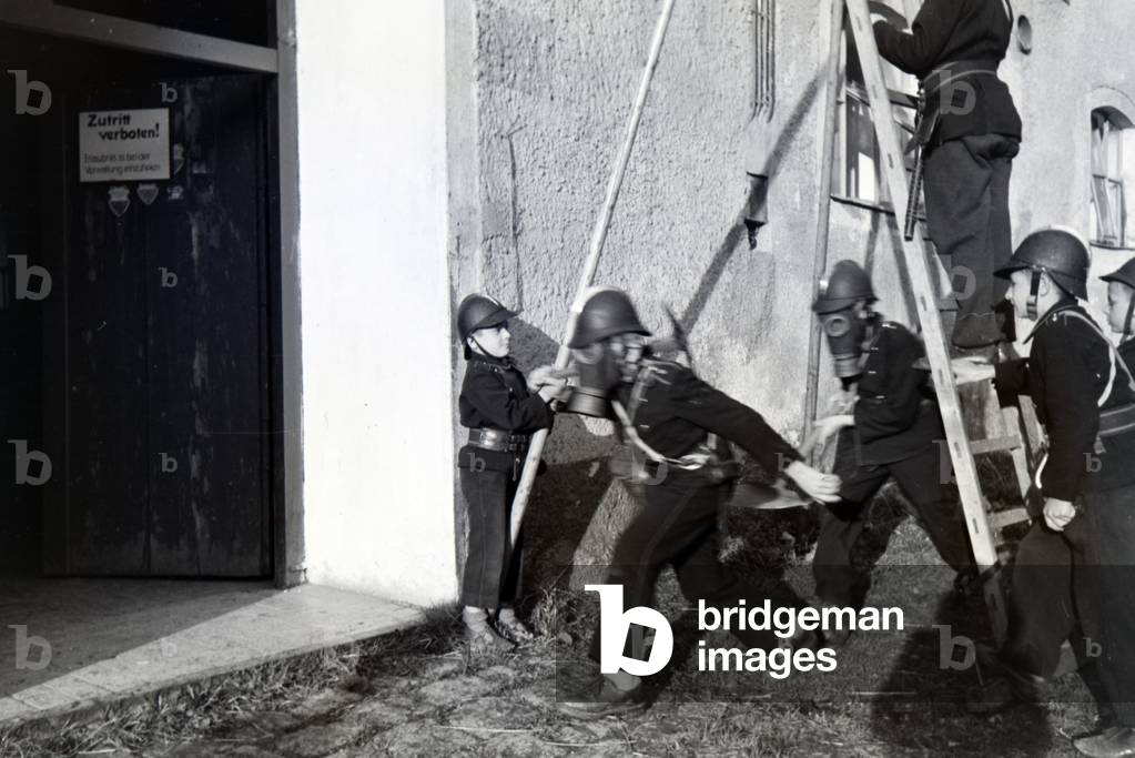 Boys wearing smoke helmets during a training of the junior firefighters, Germany 1930s (b/w photo)