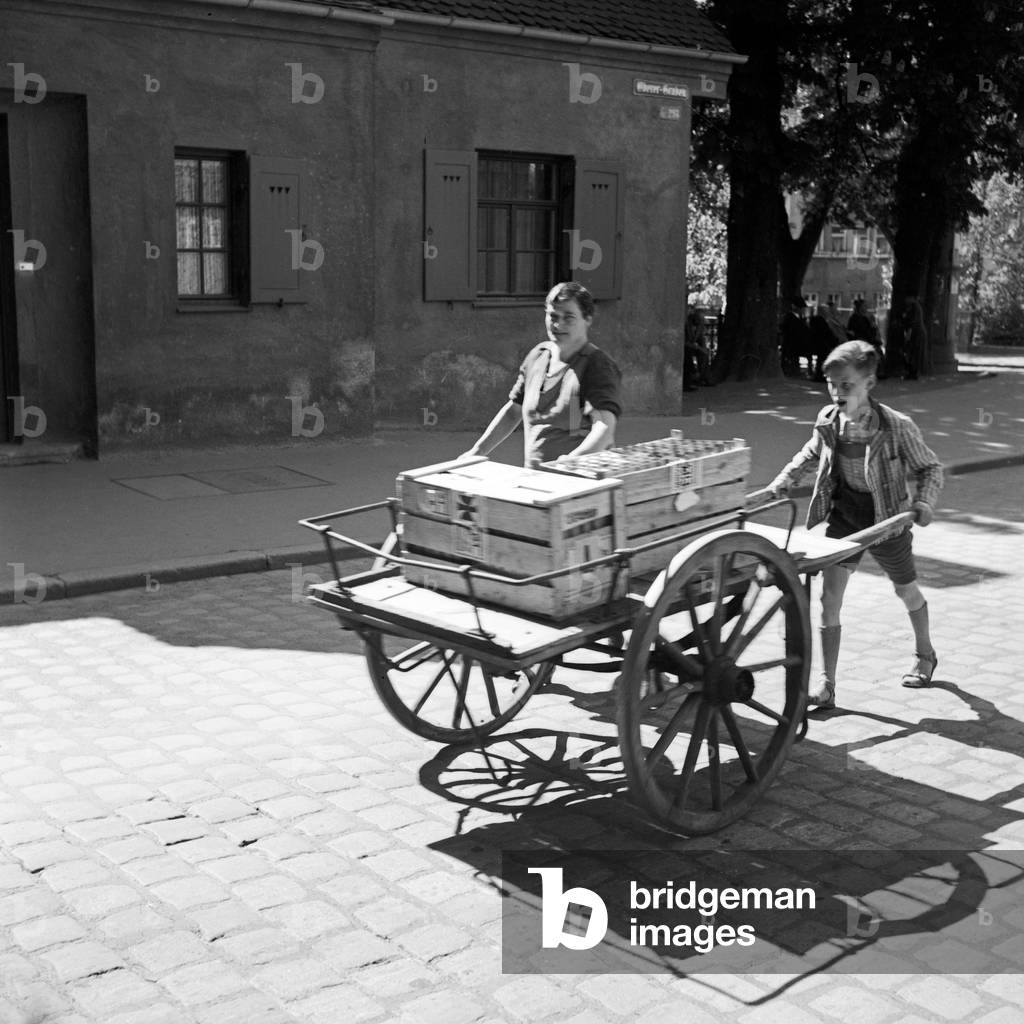 A market woman and her son pushing a cart through the streets of Augsburg, Germany 1930s (b/w photo)