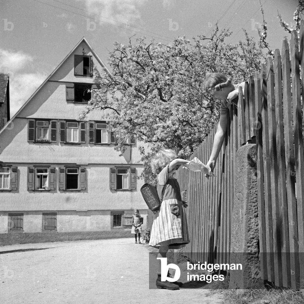 A woman giving sweets to a school kid, Germany 1930s (b/w photo)