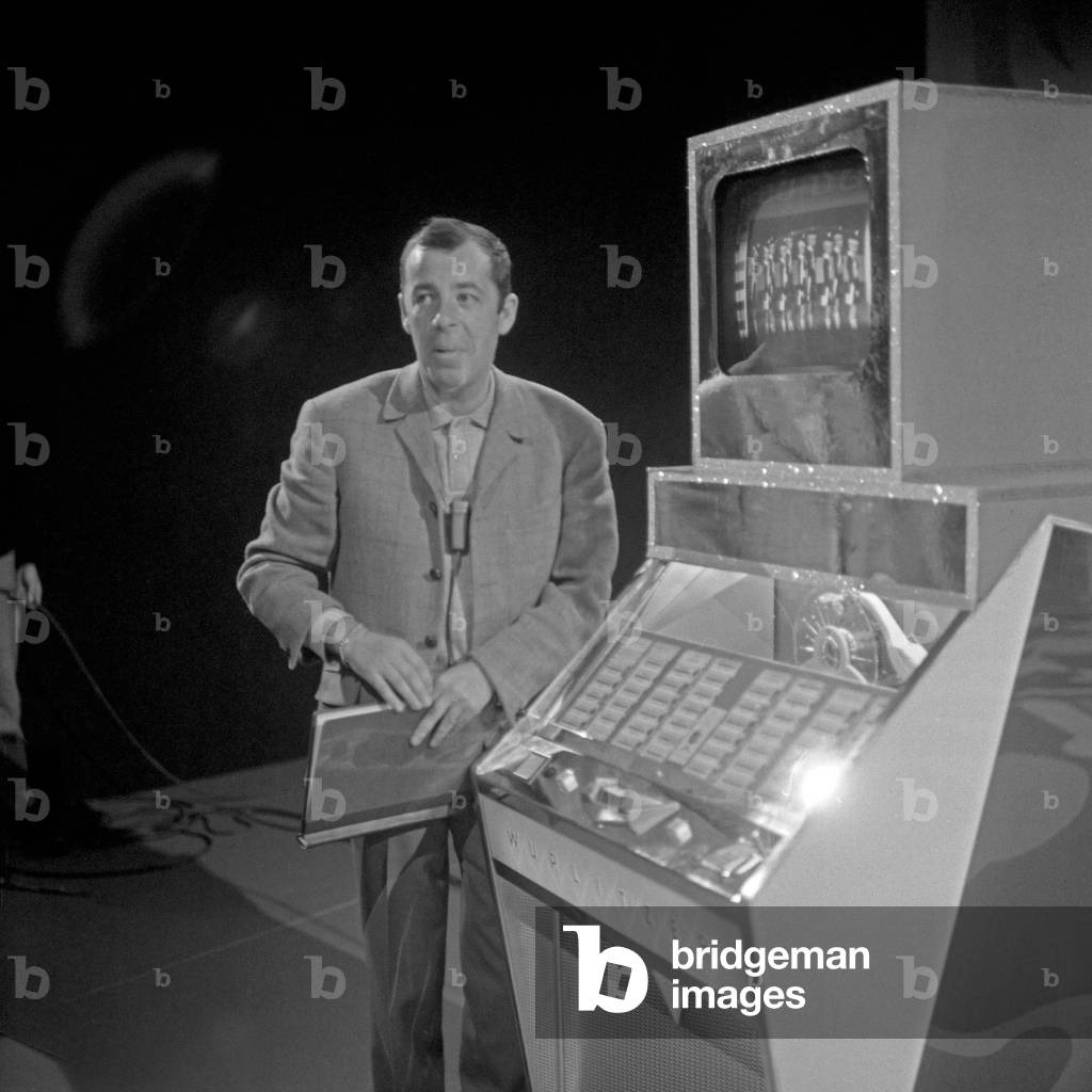 The British singer, actor, radio and TV presenter Chris Howland standing by a Wurlitzer music box, Hamburg 1960s