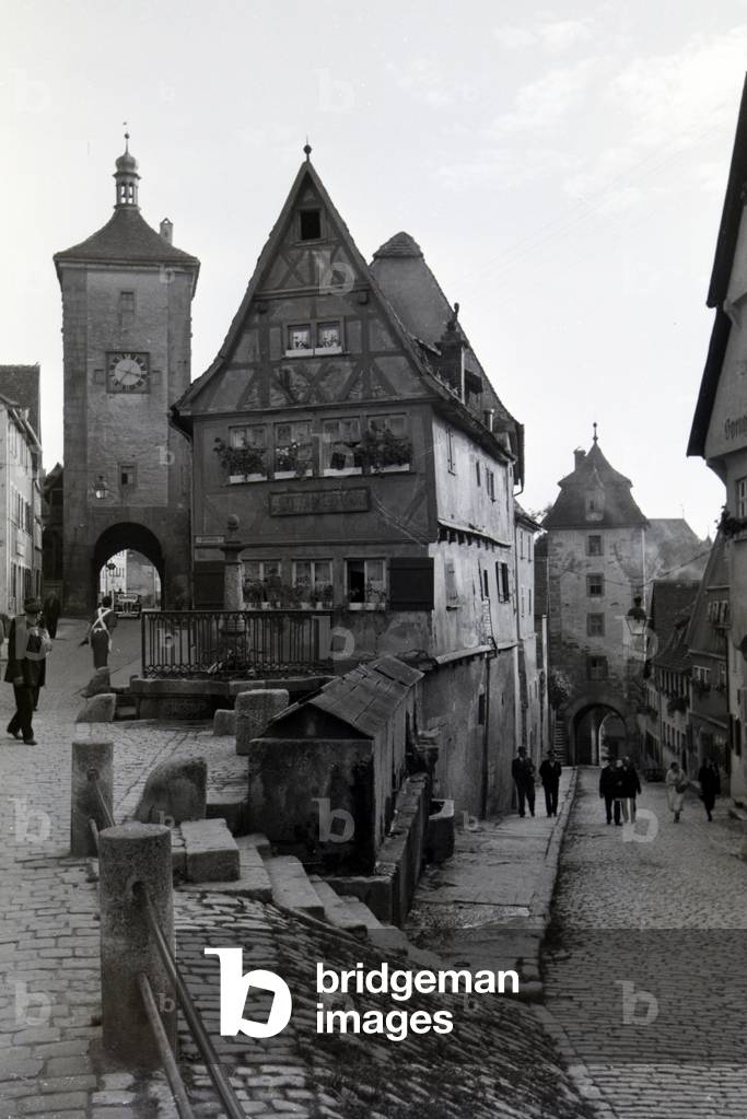 A hustle and bustle on the little square with the Siebers gate on the left and the Kobolzeller gate on the right, Rothenburg ob der Tauber, Germany 1930s (b/w photo)