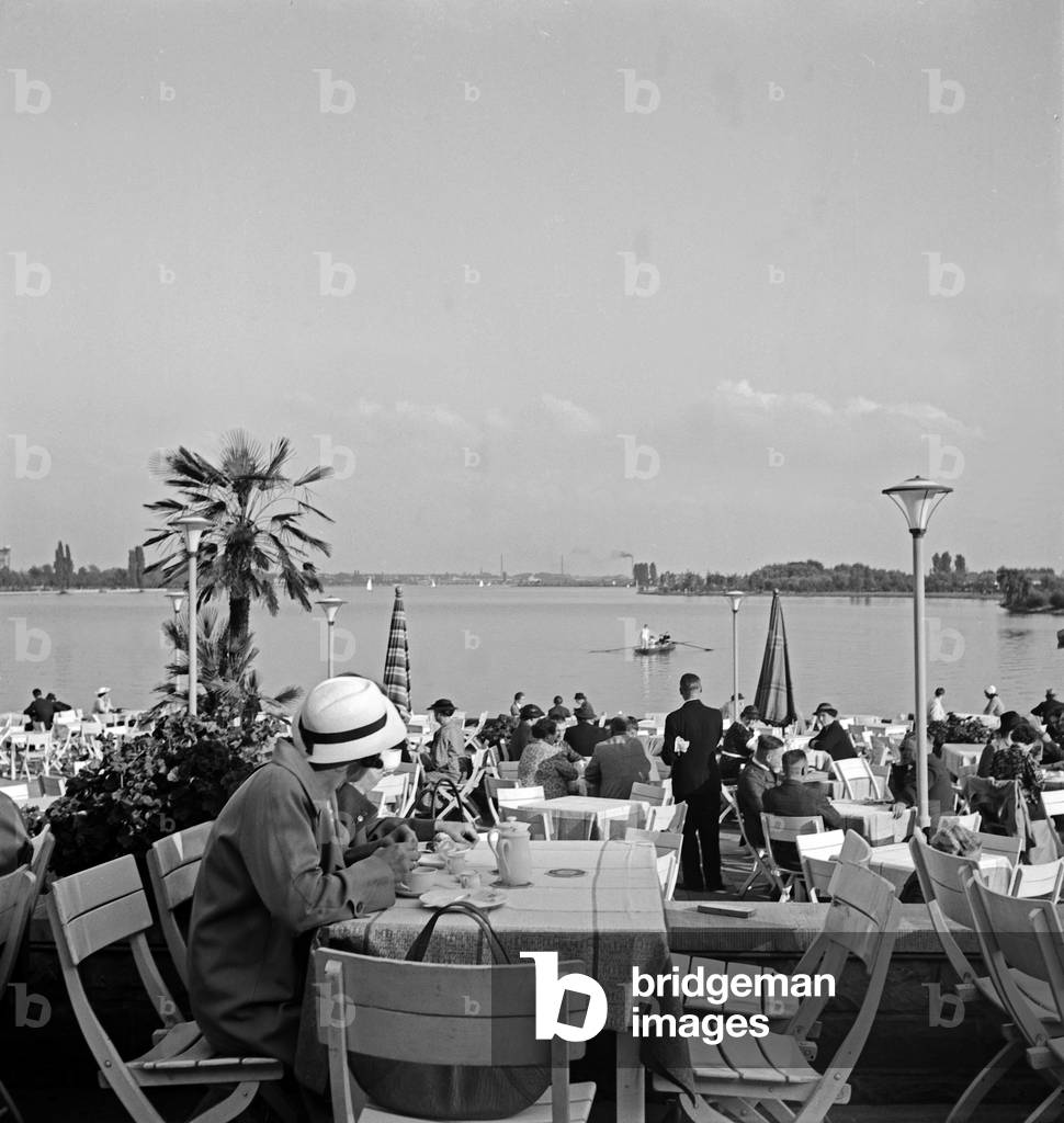 People relaxing at a garden restaurant on the shore of Maschsee lake near Hanover, Germany 1930s (b/w photo)