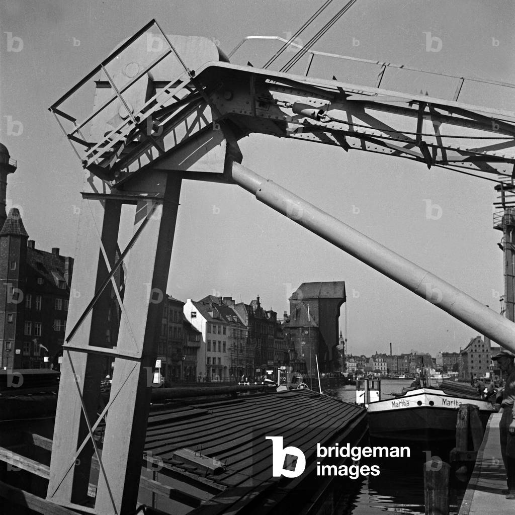 A cran at the harbor of Danzig, Krantor gate in the background, Germany 1930s (b/w photo)