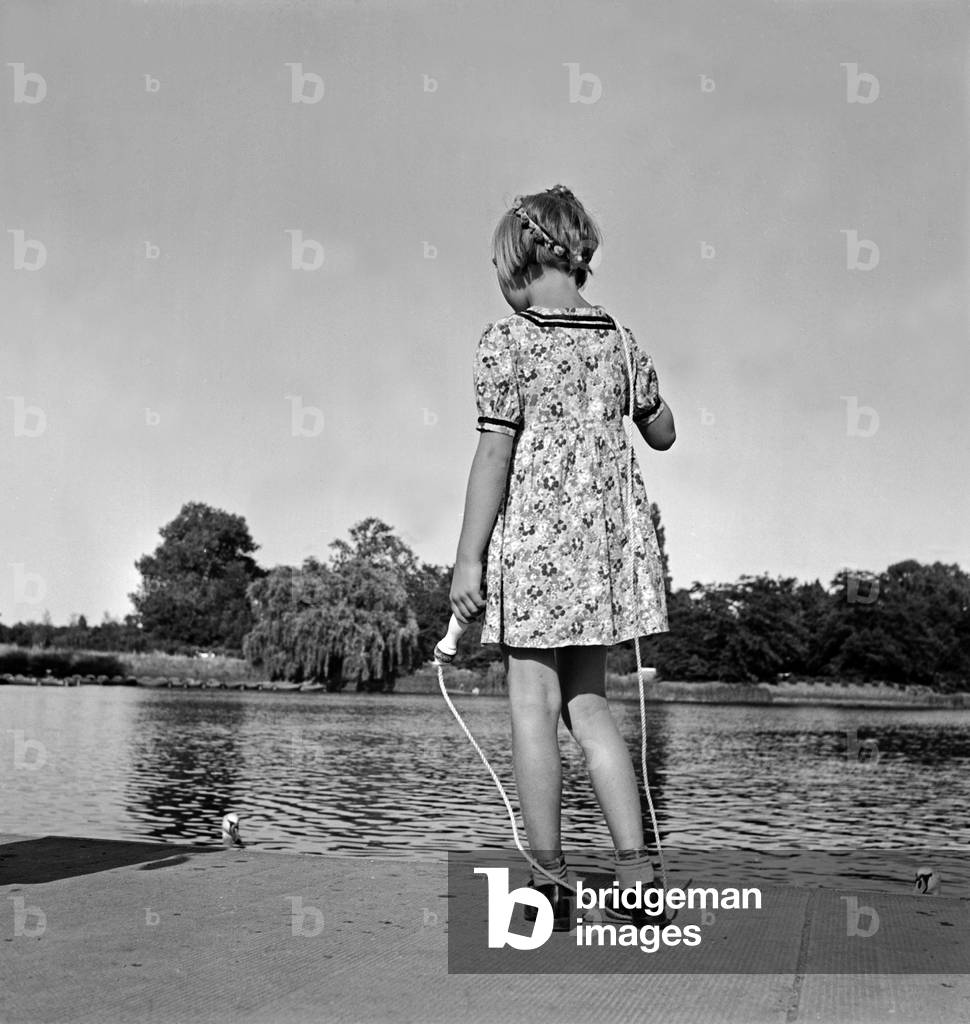 A little girl starting rope skipping at the shore of the Adolf Mittag lake at Magdeburg, Germany 1930s (b/w photo)