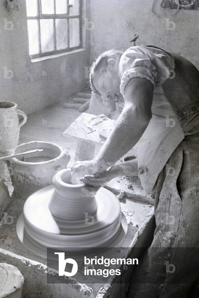 A master potter working on stoneware jars with the pottery wheel in the Kannenbäckerland, Germany 1930s (b/w photo)