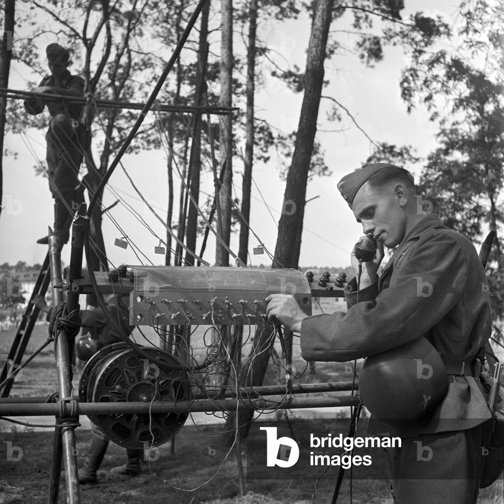 A soldier of the signal corps checking a main line near the operator car, Germany 1940s (b/w photo)