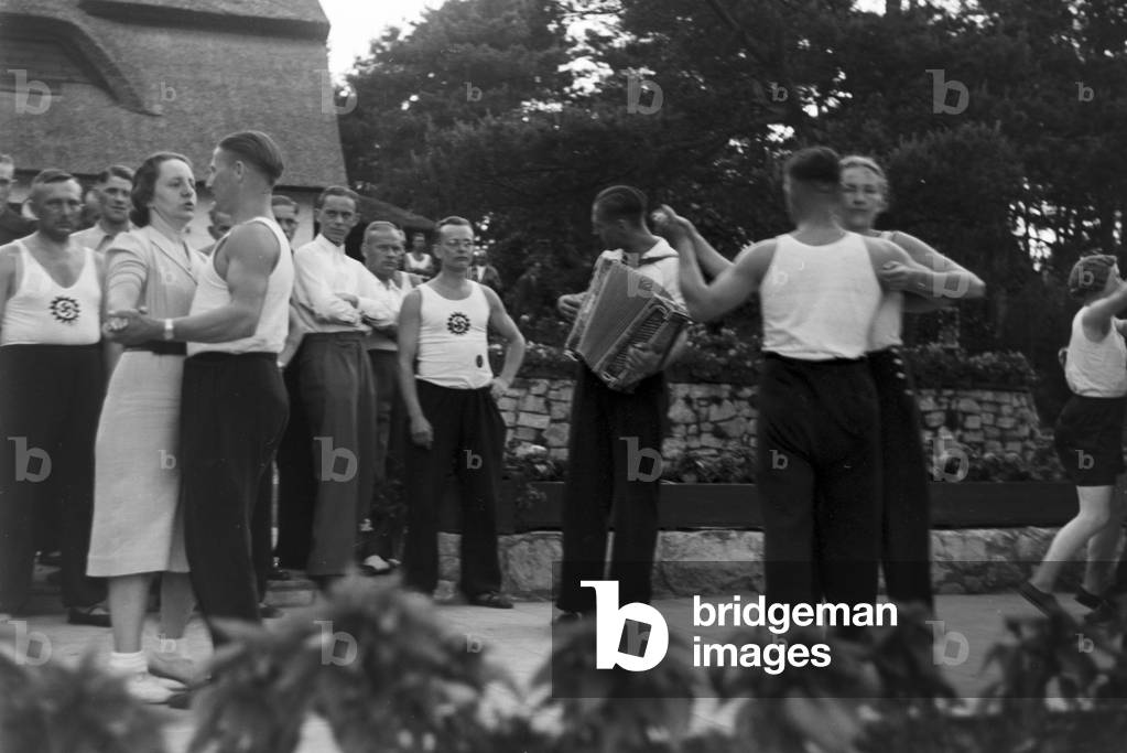 People singing and dancing in front of forest huts at the sports club at Belzig in Brandenburg, Germany 1930s (b/w photo)