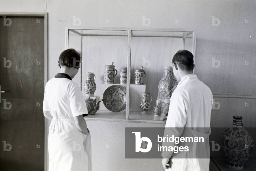 Two students of the College for Ceramics in Höhr-Grenzhausen looking at the ceramics exhibited in the hallway of the school, Germany 1930s (b/w photo)