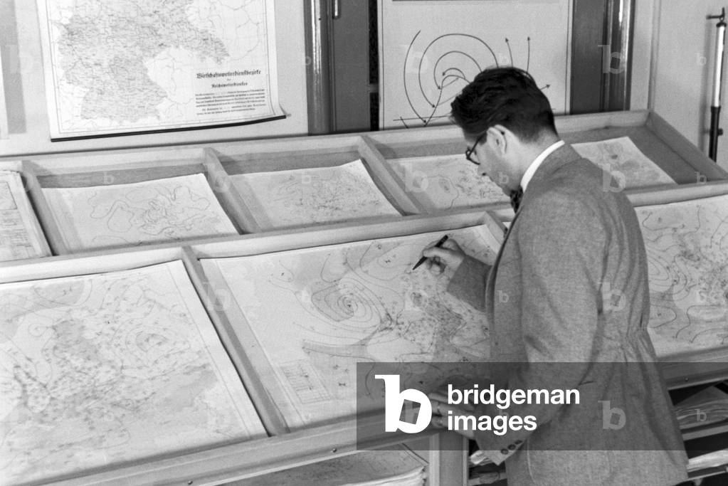 Staff member of a meteorological office drawing a card for a weather forecast, Germany 1930s (b/w photo)