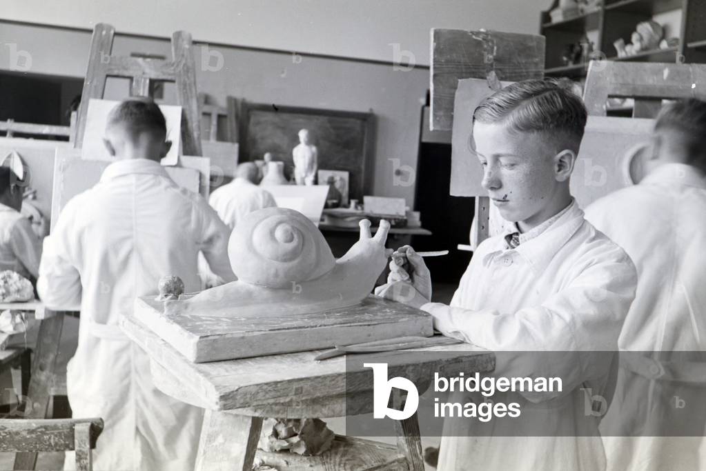 A student of the College for Ceramics working on a snail in the ateliers, Höhr-Grenzhausen, Germany 1930s (b/w photo)