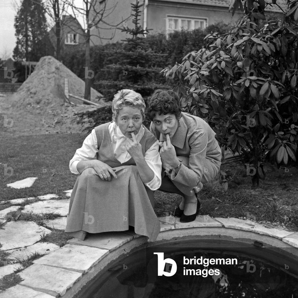 German schlager singers Margot Eskens and Friedel Hensch at a pond in the garden, Germany 1956