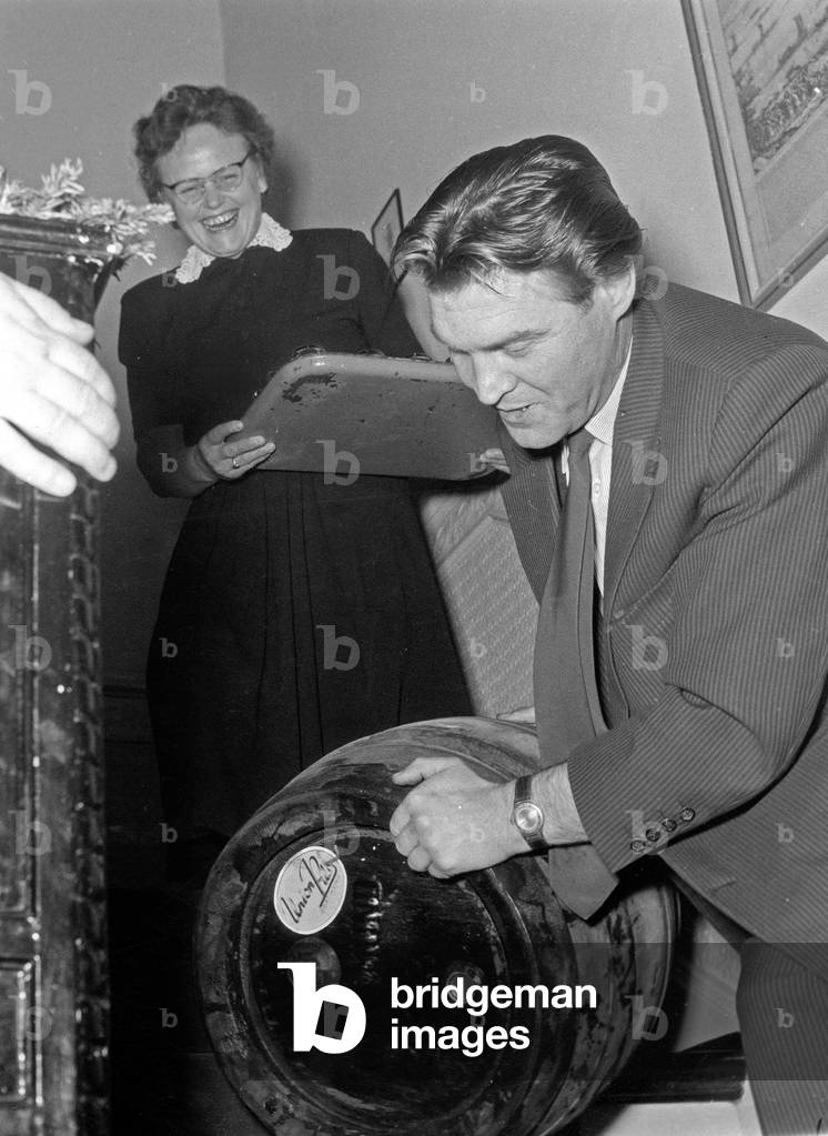 A man carrying a beer barrell to a family party, Germany late 1960s