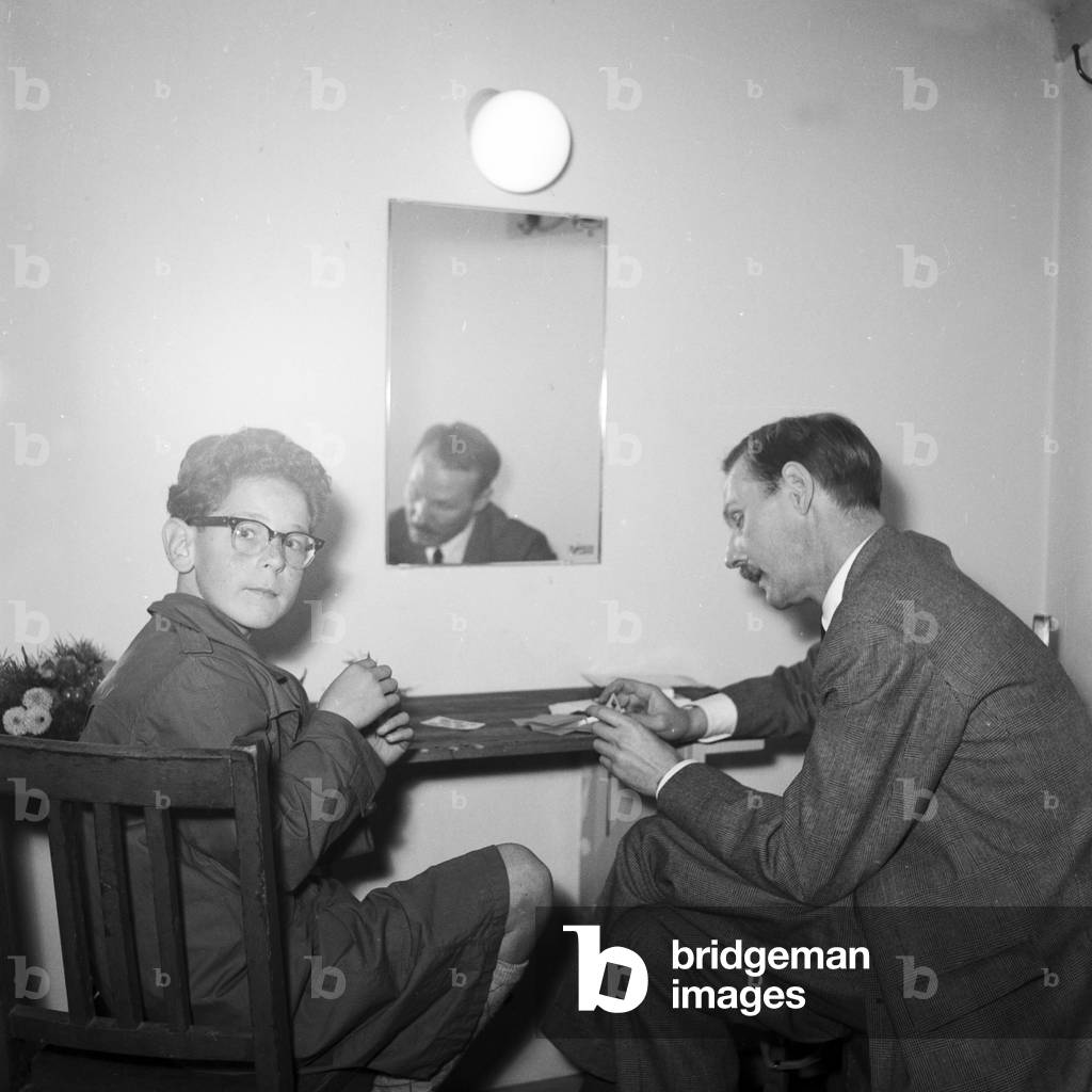 A little boy with glasses and a man sitting at a table, playing cards, Kiel, 1954