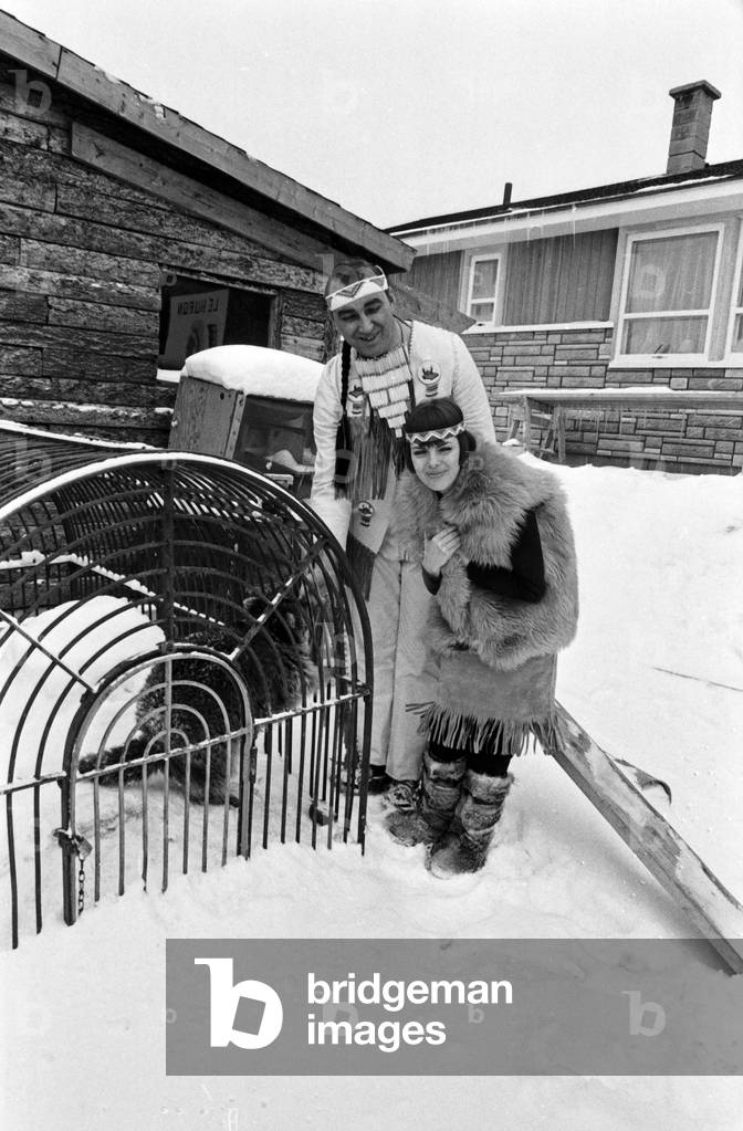 French singer Mireille Mathieu wearing a native American dress at a cage with a racoon, Germany early 1970s