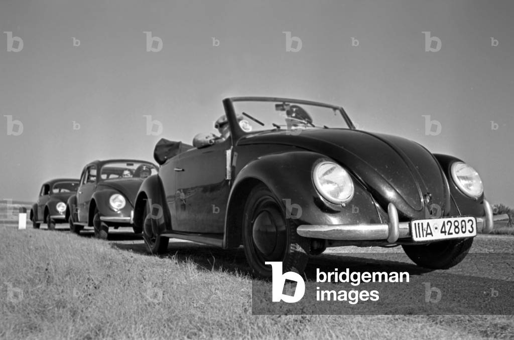Three models of the Volkswagen beetle, or KdF car, with open and closed roof and as a convertible near the test track near Wolfsburg, Germany 1930s (b/w photo)