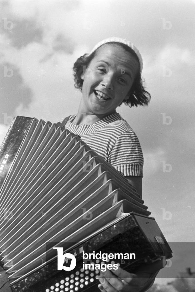 A young woman playing the harmonica, Germany 1930s (b/w photo)