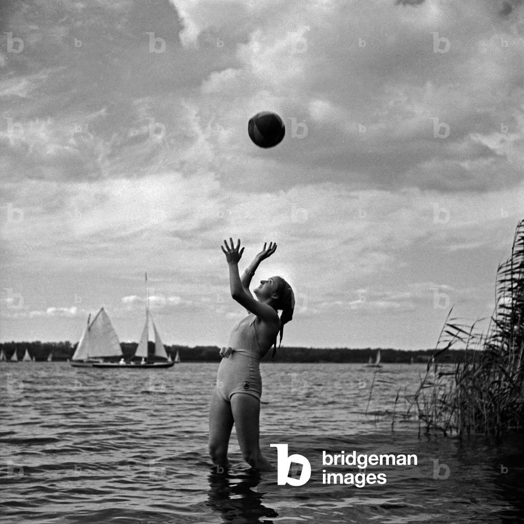 Advertising: a young woman playing waterball on a beach, Germany 1930s (b/w photo)
