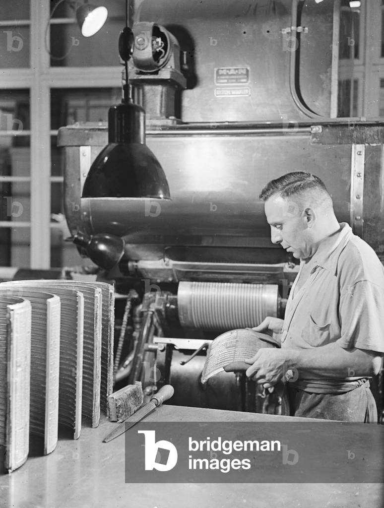 A man inserting a first print into a printing machine, Germany 1930s (b/w photo)