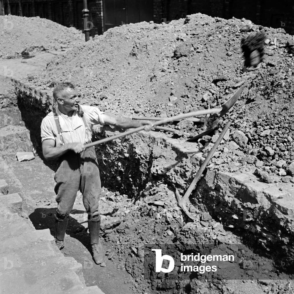 Construction worker digging at a construction area in Wuppertal, 1930s (b/w photo)