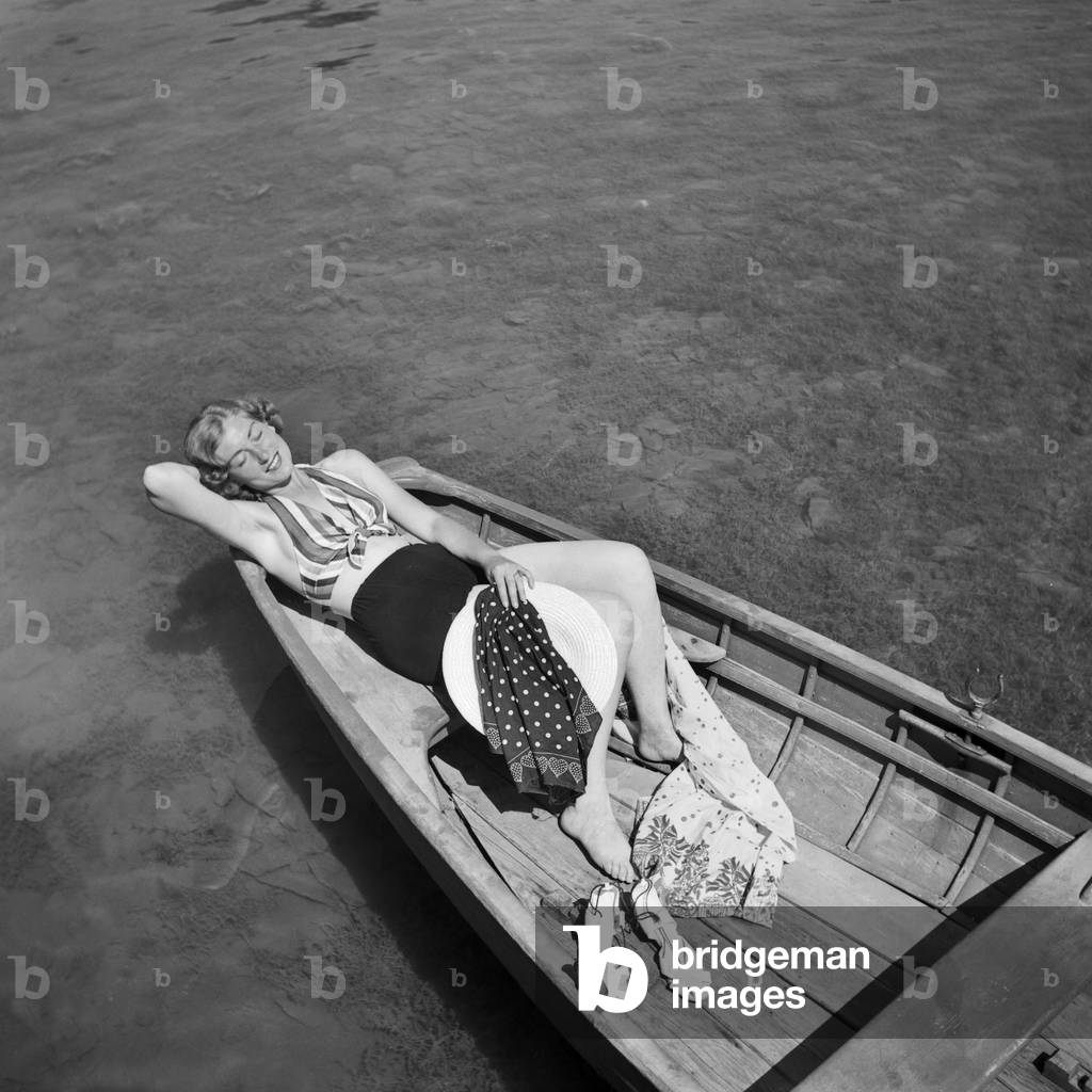 A young woman in a rowing boat on a lake in the Wachau area in Austria, Germany 1930s (b/w photo)