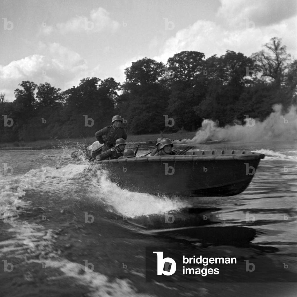 Ready for the hardest combat, soldiers of a military engineering unit are carried over a river in hostile fire, Germany 1940s (b/w photo)