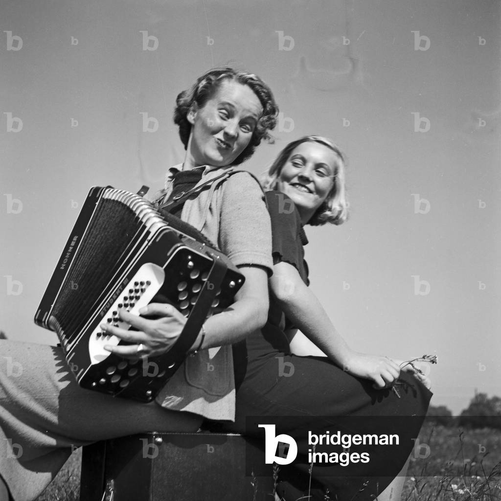 Two women playing music with an accordion, Germany 1930s (b/w photo)