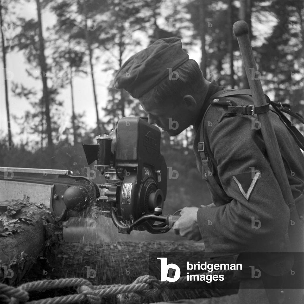 With a modern chainsaw street barricades are eliminated in seconds, Germany 1940s (b/w photo)