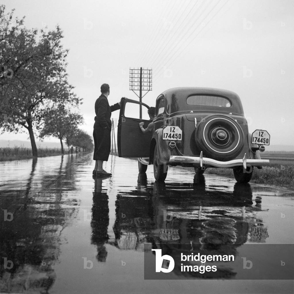 With the Ford V8 on a wet street, Germany 1930s (b/w photo)