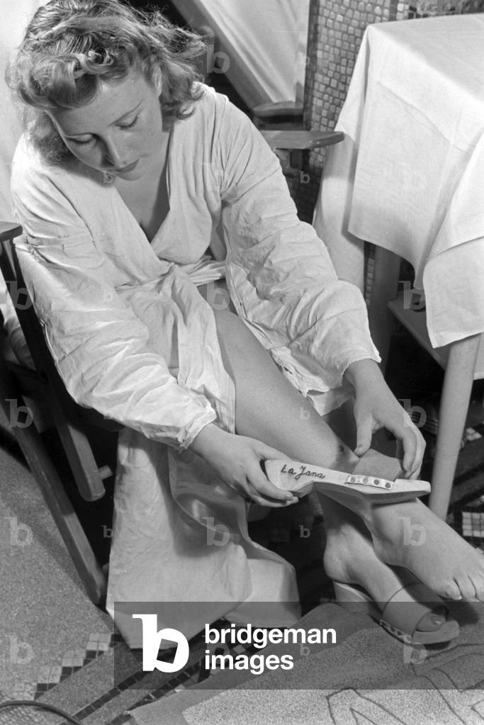 A young woman sitting in front of a mirror ar Admiralsbad bath at Berlin, holding a shoe of the series 