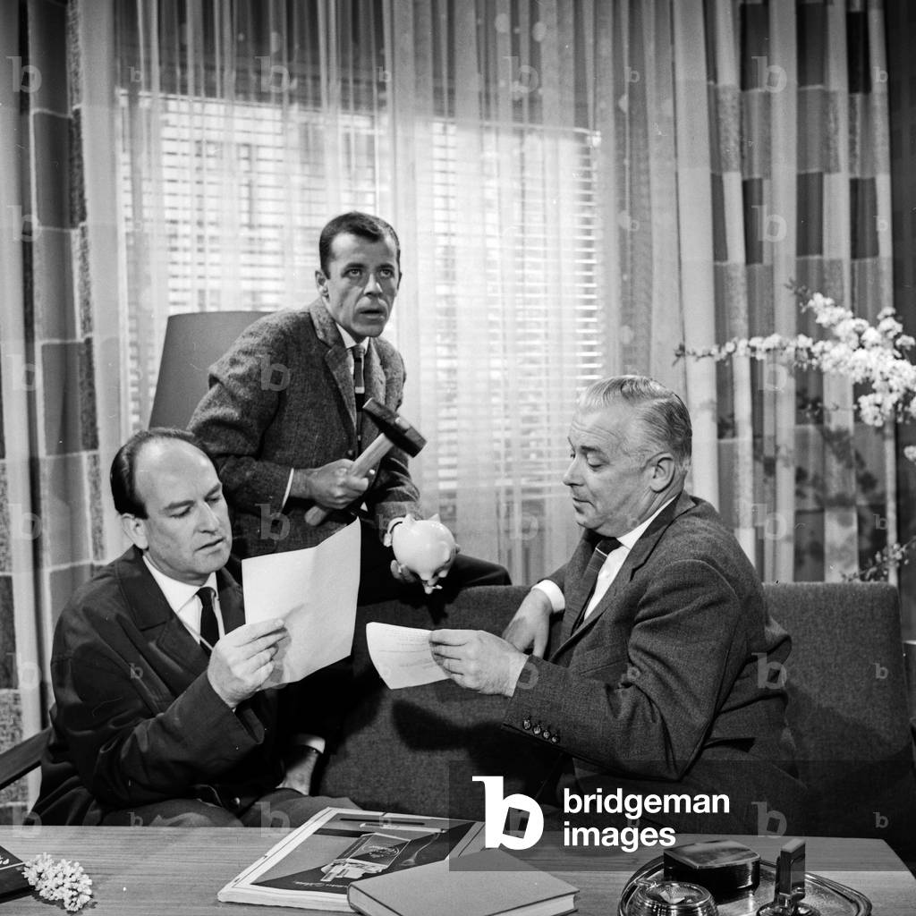 TV presenter Chris Howland (middle), director Ruprecht Essberger (left) and production manager Richert promoting Germany TV lottery 1962 at Hamburg, Germany 1960s