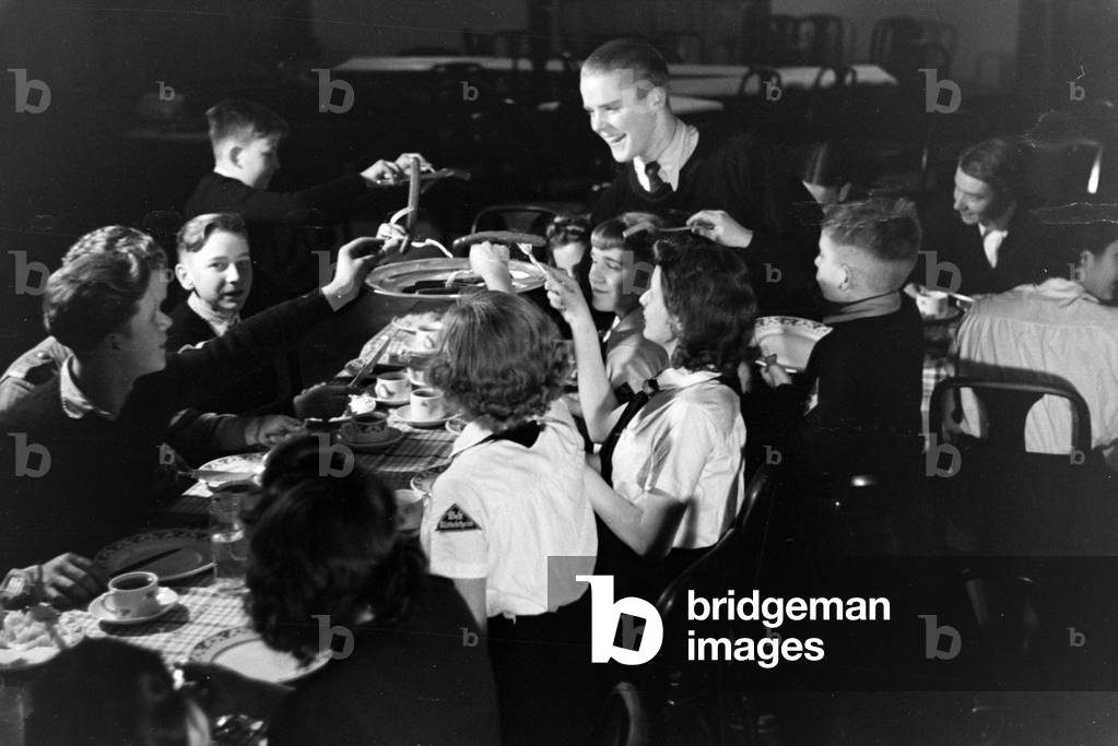 A figureskating group of the Hitler Youth wearing uniforms of the HJ and BDM during dinner after a training, Germany 1930s