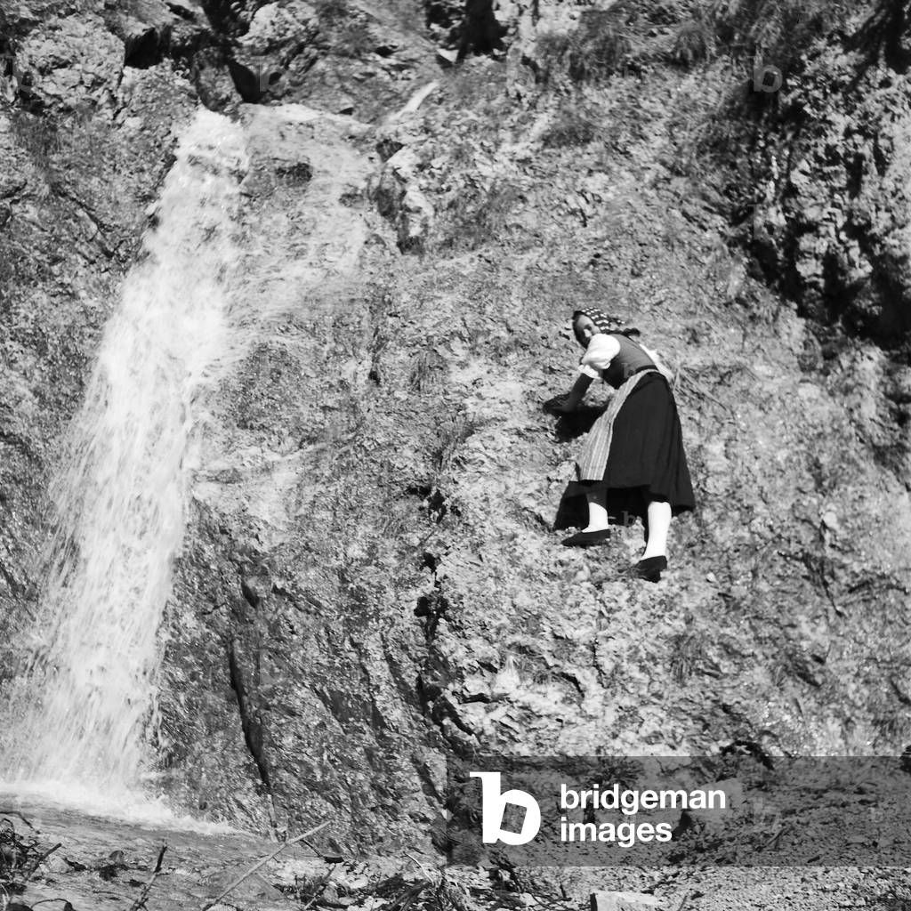 A young woman climbing on a mountain in the Wachau area in Austria, Germany 1930s (b/w photo)