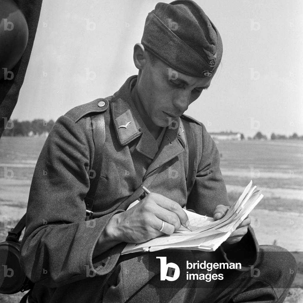 Soldier of the signal corps recording a dictated note from his comrade, Germany 1940s (b/w photo)