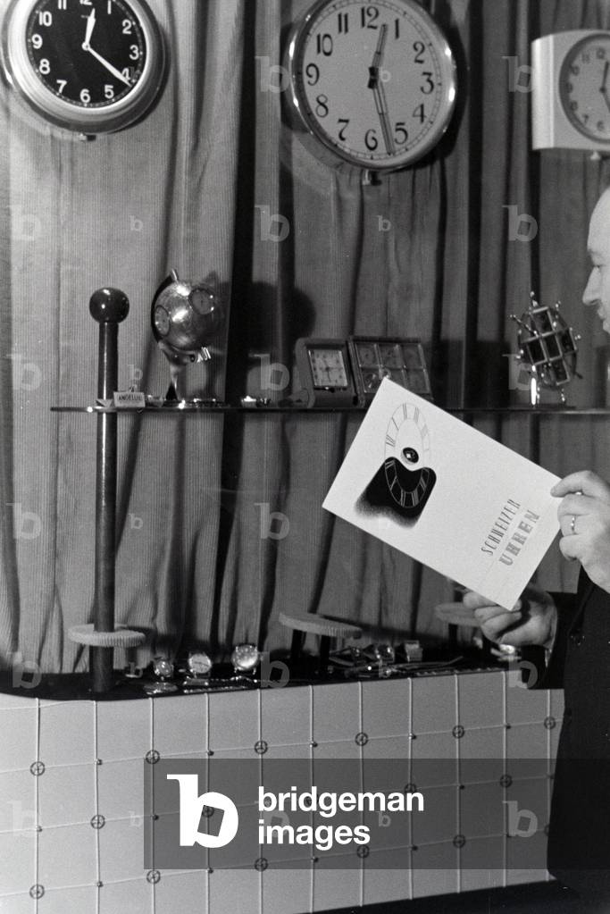 A visitor on the Leipziger Frühjahrsmesse in front of a stand with Swiss clocks, Germany 1941 (b/w photo)