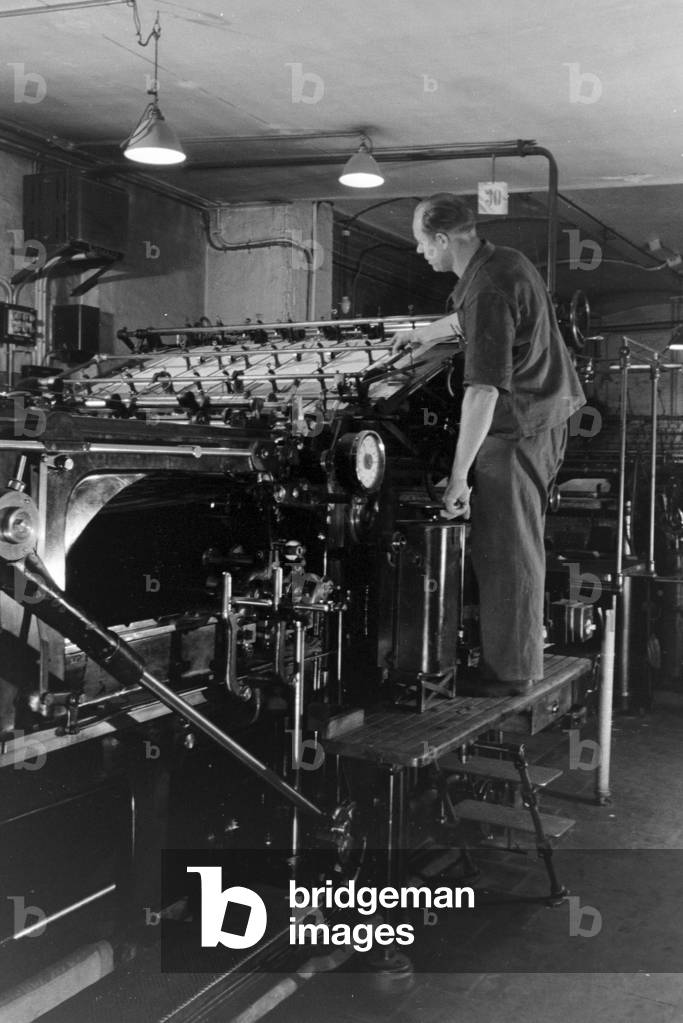 A printer controlling the rotary printing press in the plants of the mechanical engineering company MAN (Maschinenfabrik Augsburg-Nürnberg), Germany 1930s (b/w photo)