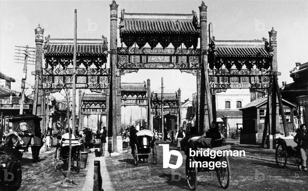 Rickshas on their way through the city gate into the city, China, 1910s