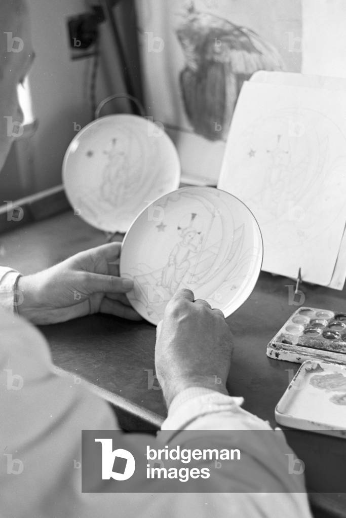 A porcelain painter is drawing a Christmas motive on a plate in the workshops of the State Porcelain Manufactory Berlin, Germany 1930s (b/w photo)