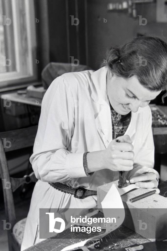 Woman punchinging different leather goods, Germany 1930s (b/w photo)