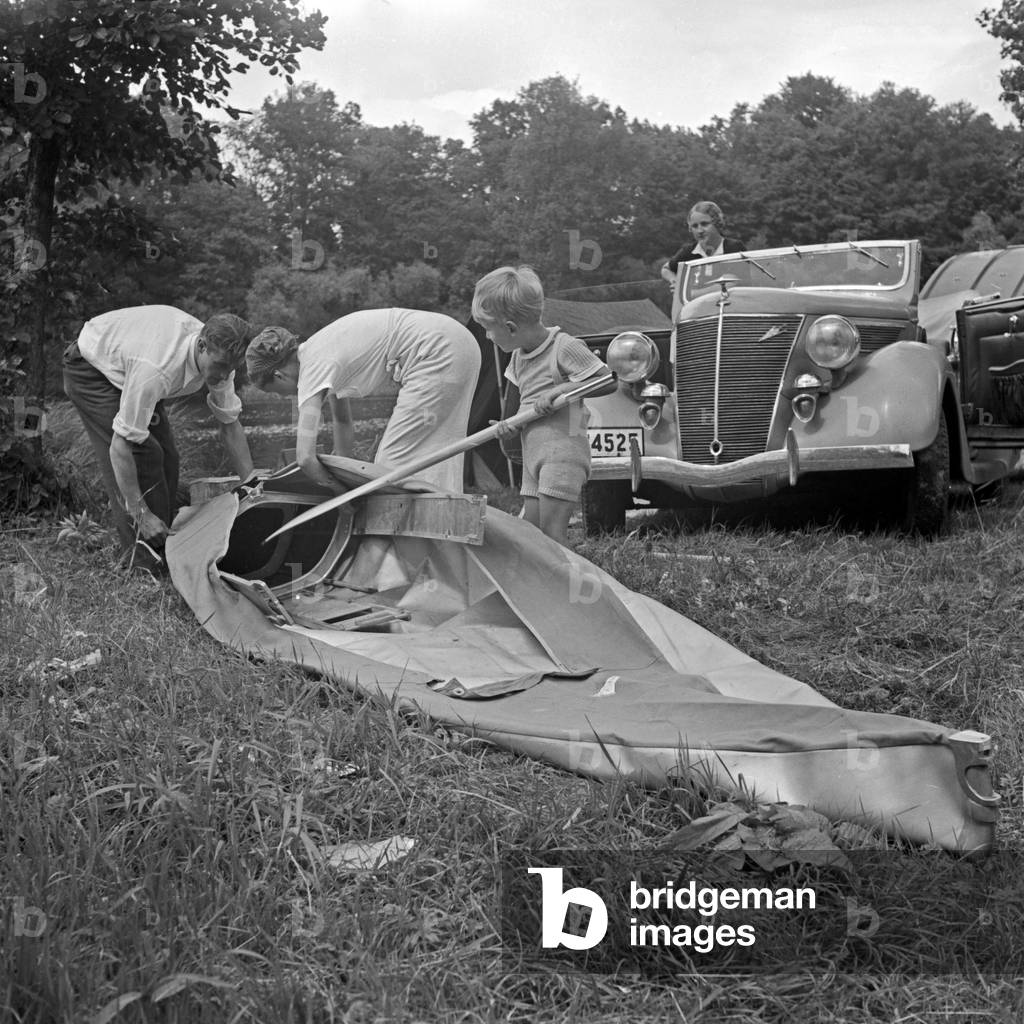 A family packing the Klepper folding boat, a Ford V8 in the background, Germany 1930s (b/w photo)