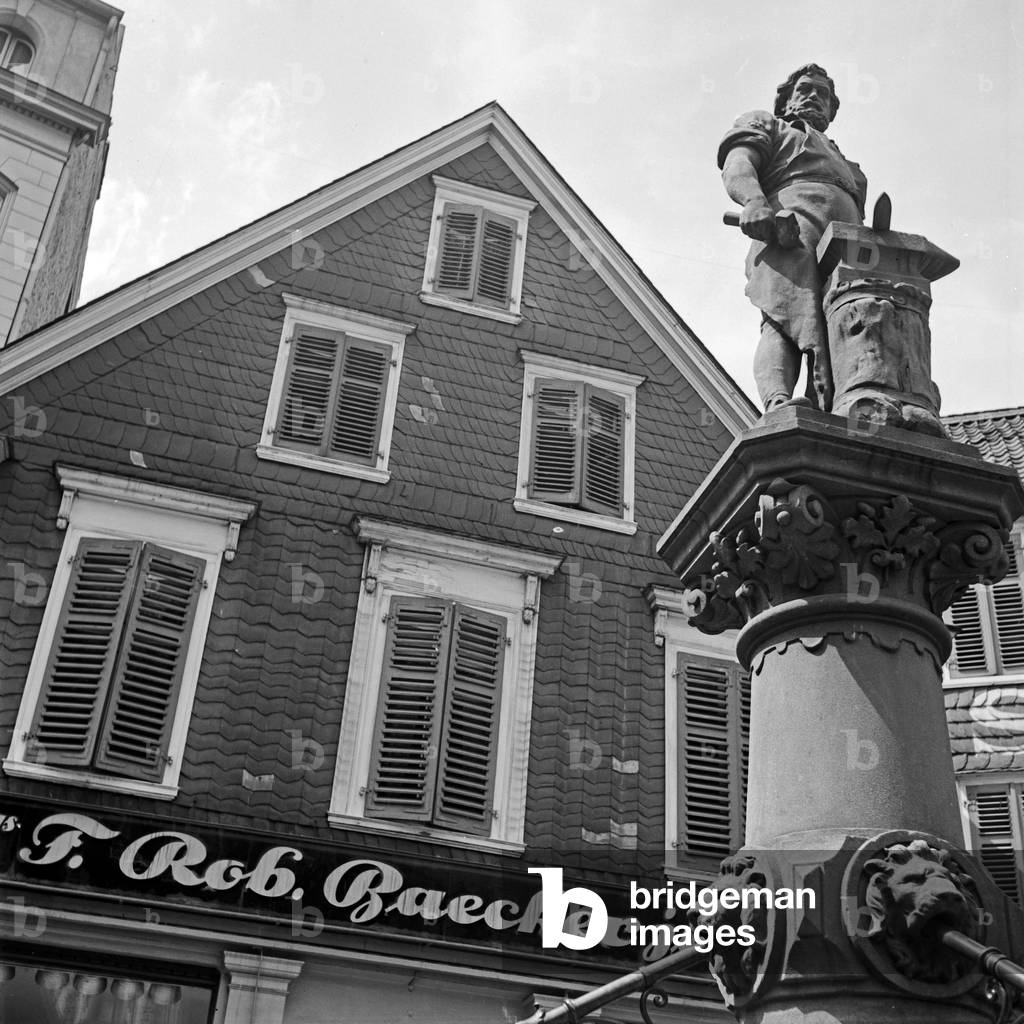 Monument of the brave blacksmith Peter Hahn in front of fashion store Baecker at the old main market at Solingen, Germany 1930s (b/w photo)